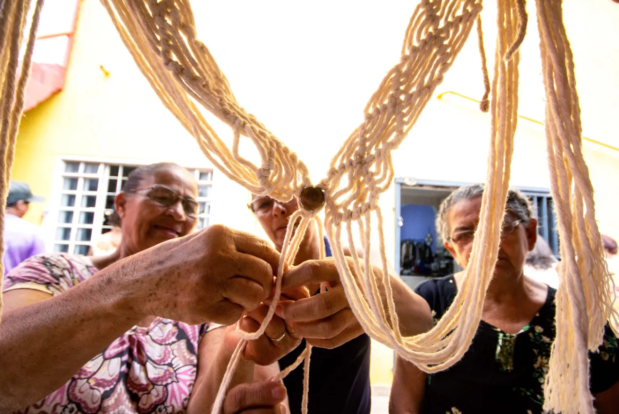 Mãos de mulheres tecendo macramê juntas